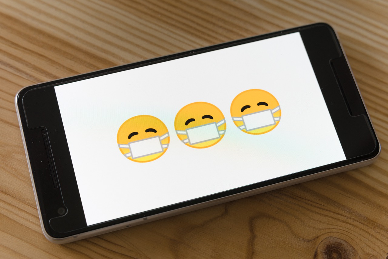 Trzy emoji w maseczkach przeciwwirusowych wyświetlone na telefonie