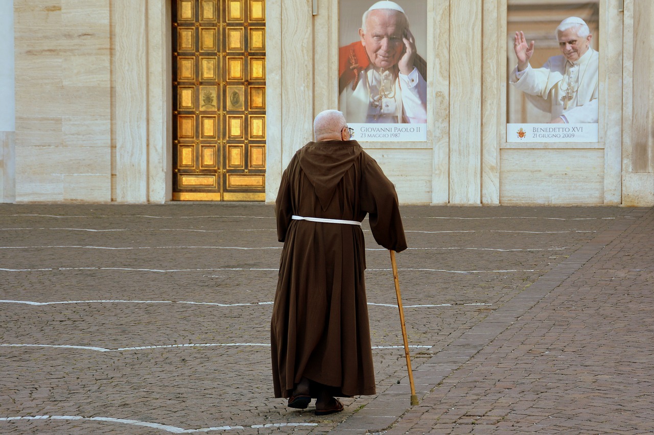 Zakonnik patrzący na portrety dwóch papieży